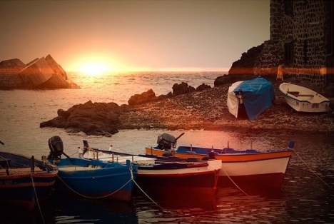 spiagge pozzillo al tramonto con tre barche.